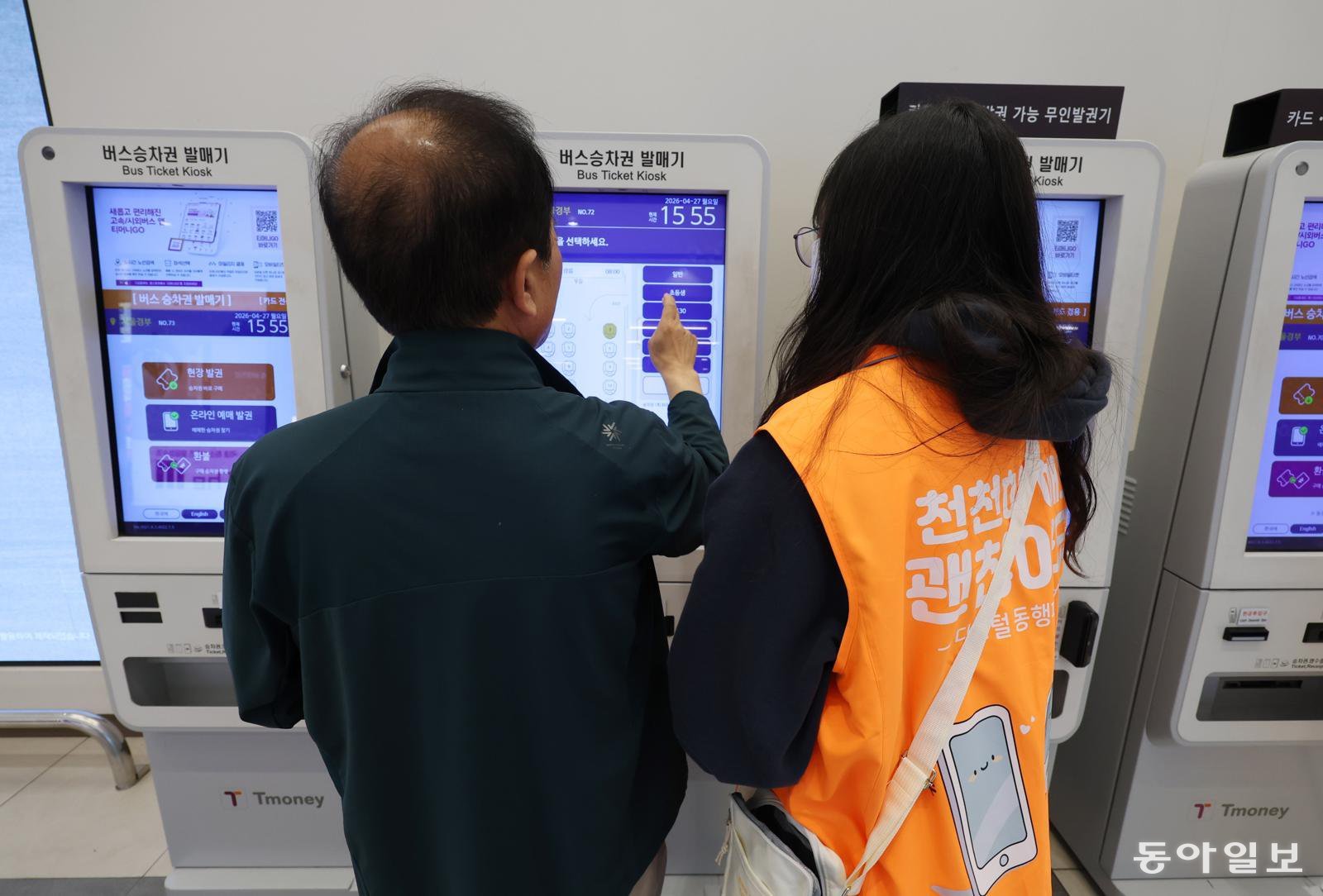 27일 오후 서울 고속버스터미널 무인 발권기 앞에서 주황색 조끼를 입은 ‘디지털 동행파트너’ 자원봉사자가 어르신에게 발권 방법을 안내하고 있다. 신원건 기자 laputa@donga.com