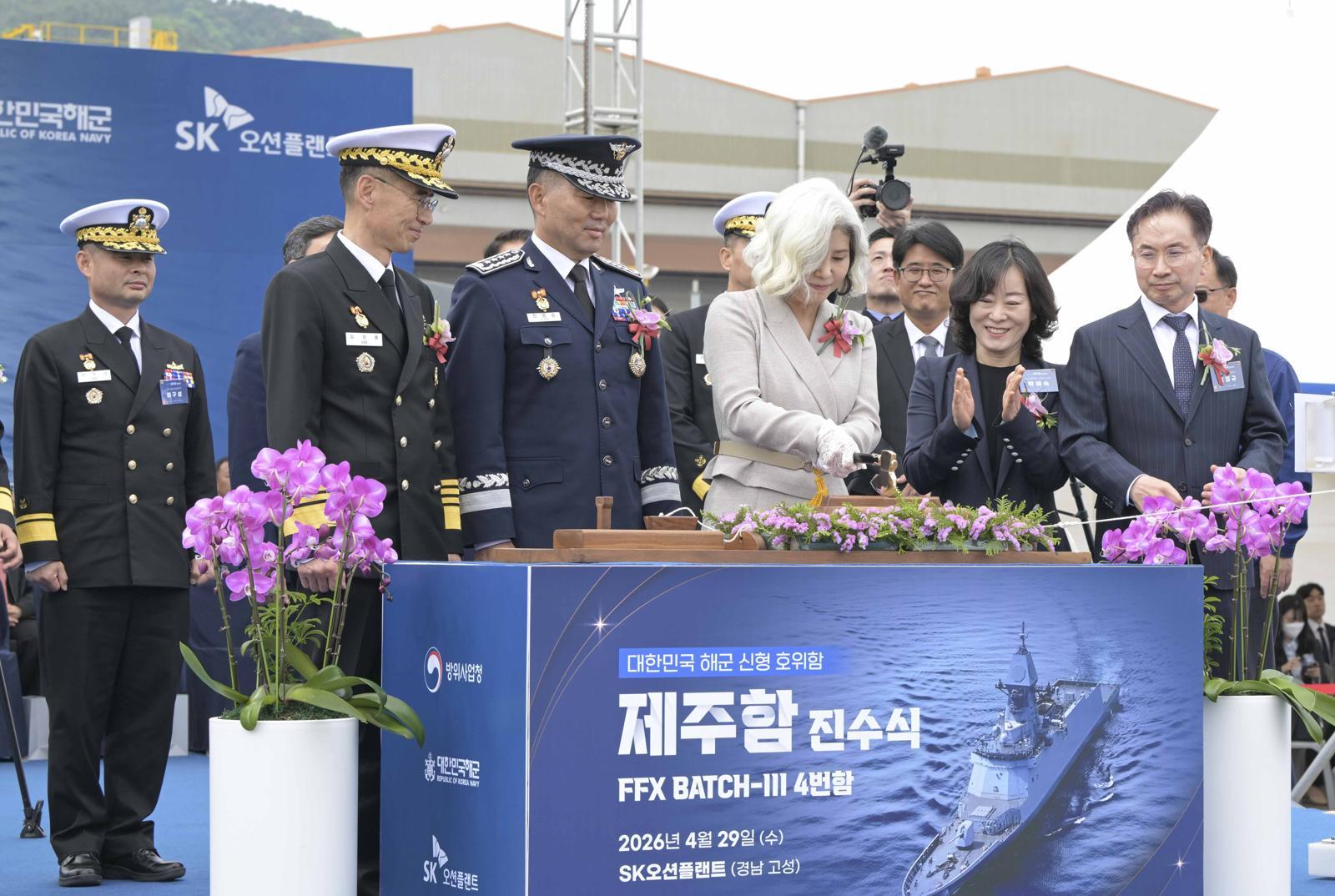 29일 경남 고성군 SK오션플랜트에서 열린 제주함 진수식에서 진영승 합참의장의 부인 정애숙 여사가 진수도끼를 이용해 진수줄을 자르고 있다. 해군 제공