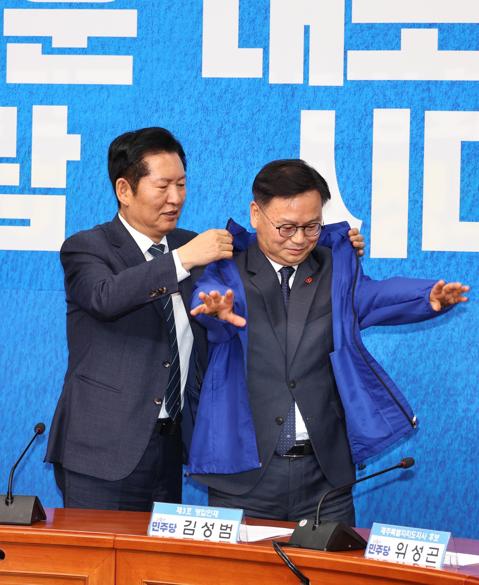 정청래 더불어민주당 대표가 30일 오전 서울 여의도 국회에서 열린 3차 인재영입식에서 김성범 전 해양수산부 차관에게 당점퍼를 입혀주고 있다. 뉴시스