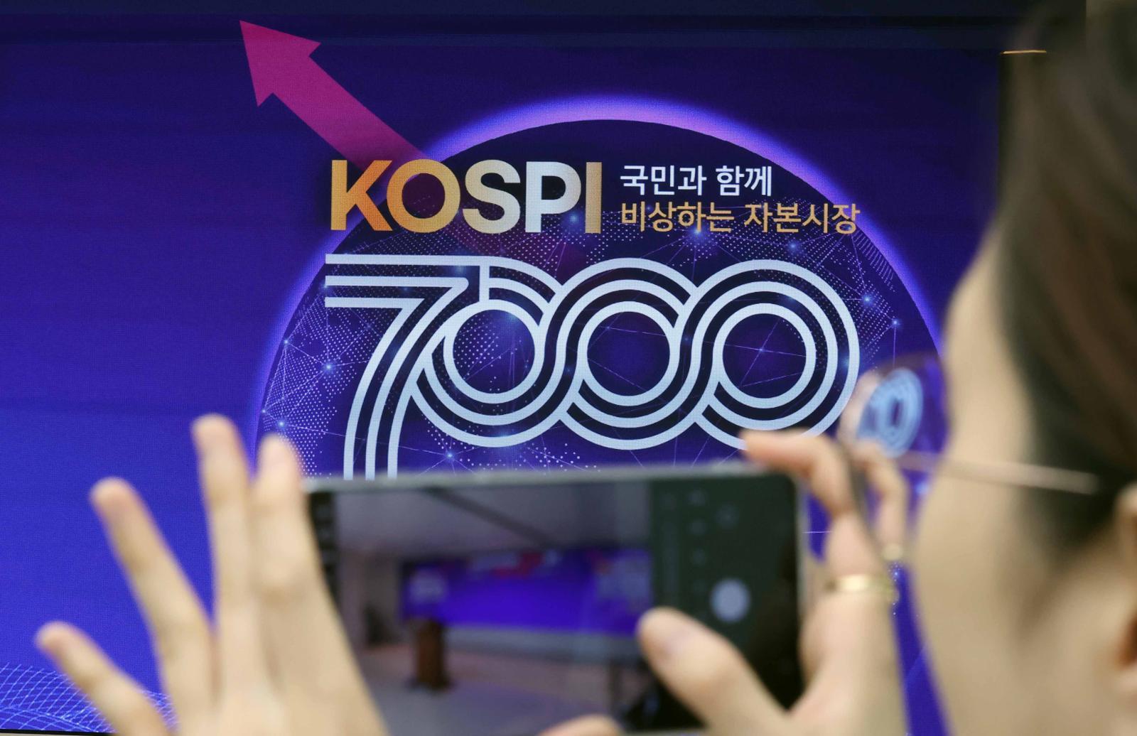 사상 처음으로 코스피 7000p를 돌파한 6일 부산 남구 부산국제금융센터 내 한국거래소 홍보관에서 열린 축하행사에 참석한 한 관계자가 휴대전화로 촬영하고 있다. 2026.05.06. 뉴시스