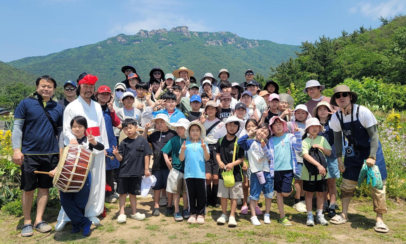 스승의 날을 하루 앞둔 14일 경남 남해 상주초 학생과 학부모, 교사가 학교 인근 논에서 모내기 체험을 한 뒤 사진 촬영을 하고 있다. 학부모들은 15일 일일 교사로 나서 스승의 날을 기념한다. 남해 상주초 제공