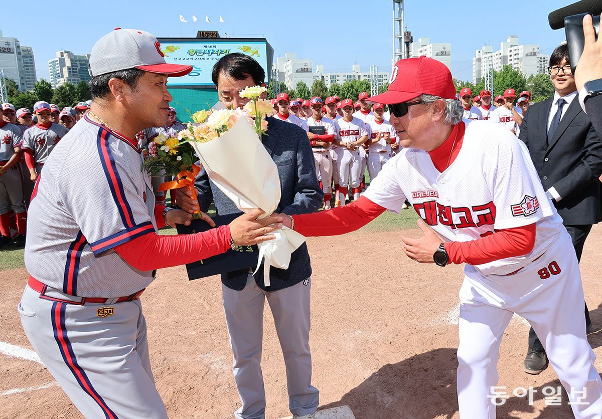 16일 황금사자기 결승전 이후 대전고 김의수 감독(오른쪽)이 감독상을 받은 충암고 이영복 감독에게 꽃다발을 건네며 축하하고 있다. 전영한 기자 scoopjyh@donga.com
