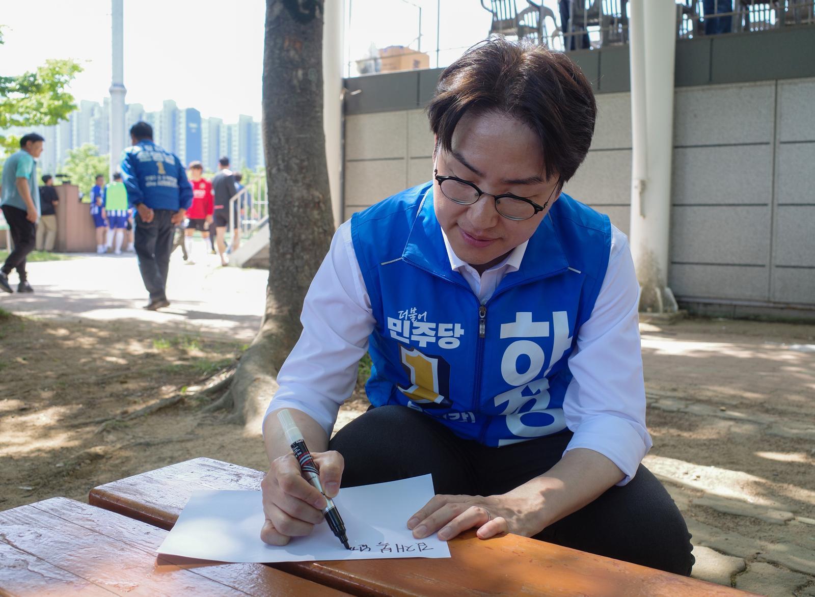 하정우 더불어민주당 부산 북구갑 국회의원 보궐선거 후보가 17일 부산 북구 화명생태공원에서 열린 북구축구협회장기 대회 현장에서 한 주민에게 사인을 해주고 있다. 2026.05.17. 뉴스1