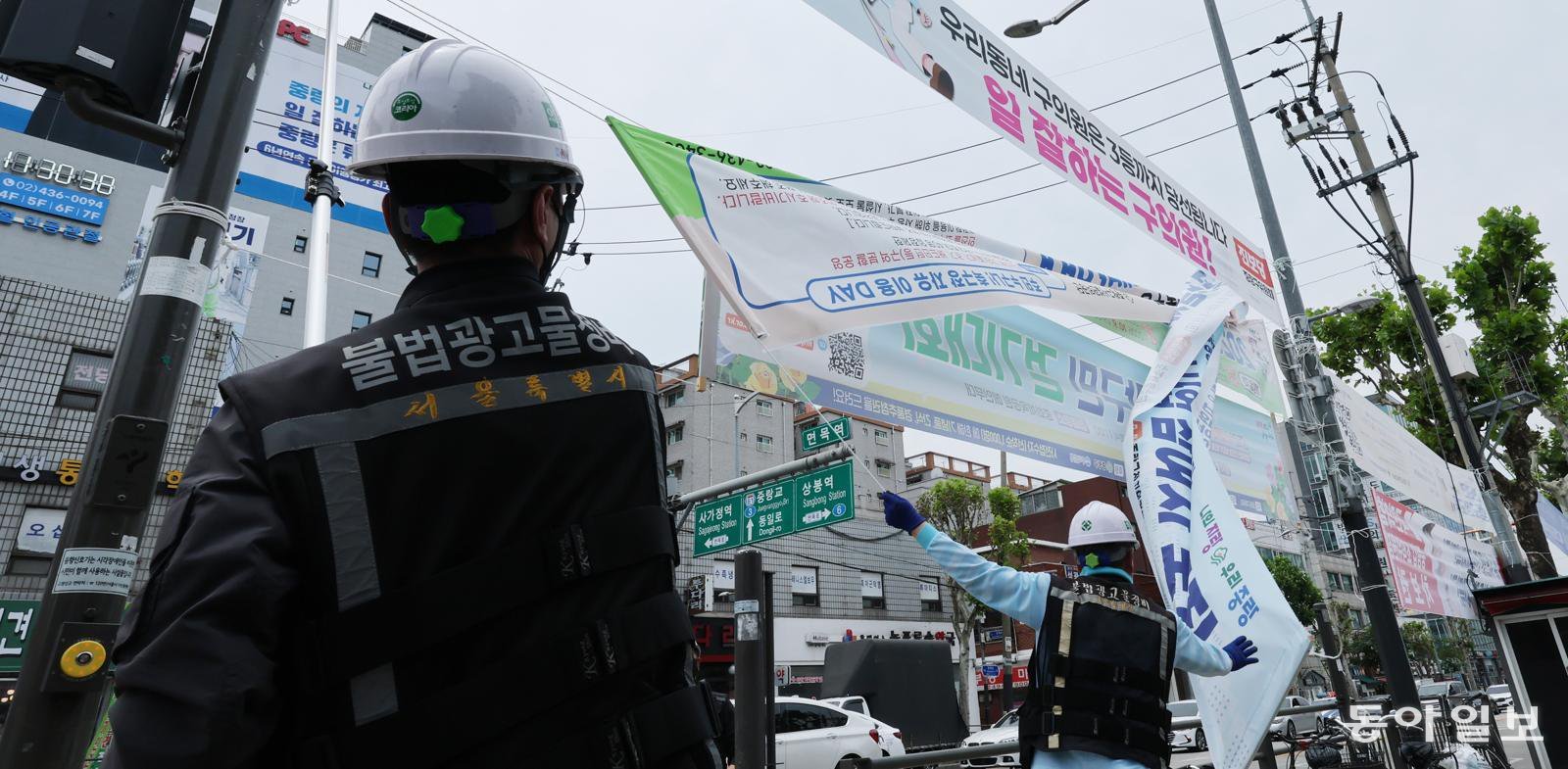 19일 서울시 불법 현수막 기동정비반이 중랑구 면목역 사거리 일대에 걸린 불법 현수막을 철거하고 있다. 이날 서울시는 중랑구 일대에서 7개의 불법 현수막을 단속해 철거했다. 신원건 기자 laputa@donga.com