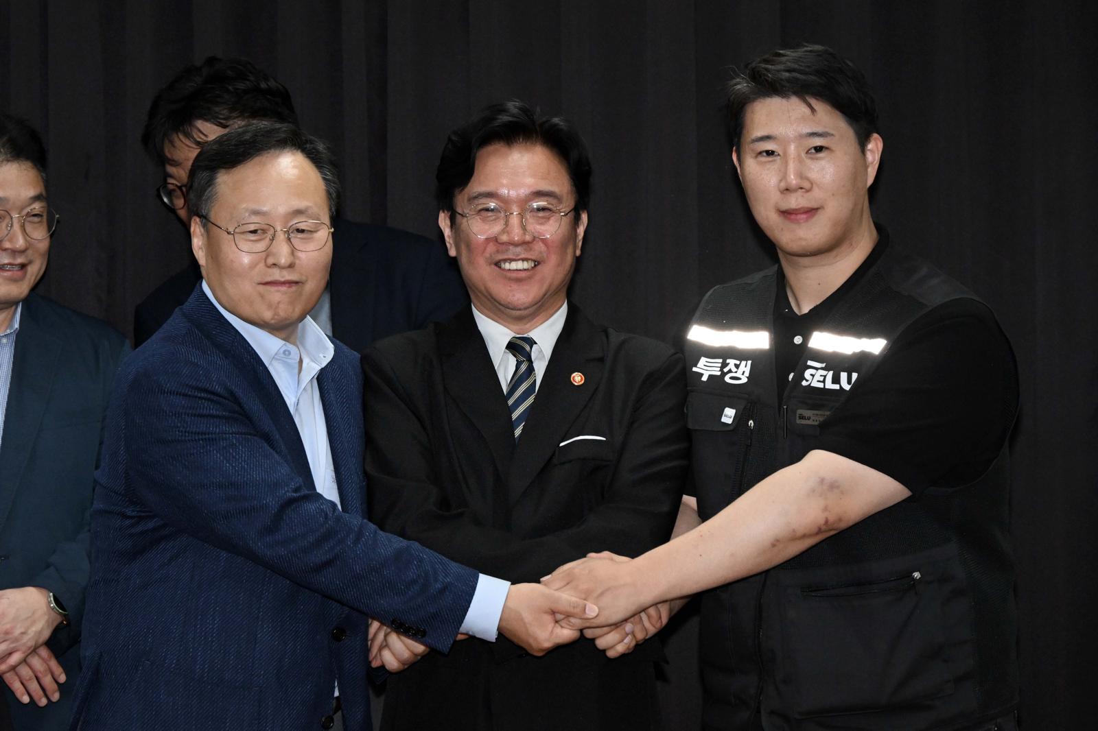 20일 경기도 수원시 장안구 경기고용노동청에서 열린 삼성전자 임금협상을 마친 후 여명구 삼성전자 DS(디바이스솔루션·반도체 사업 담당) 피플팀장과 김영훈 고용노동부 장관, 최승호 삼성그룹 초기업노동조합 삼성전자지부 위원장이 잠정 합의한에 서명한 후 손을 맞잡고 있다. (공동취재) 2026.5.20 ⓒ 뉴스1