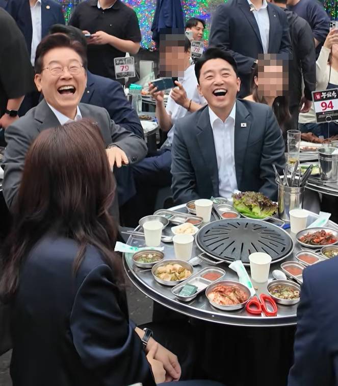 식당 야외테이블에서 2층 손님을 바라보며 환하게 웃는 이재명 대통령. 유튜브 갈무리
