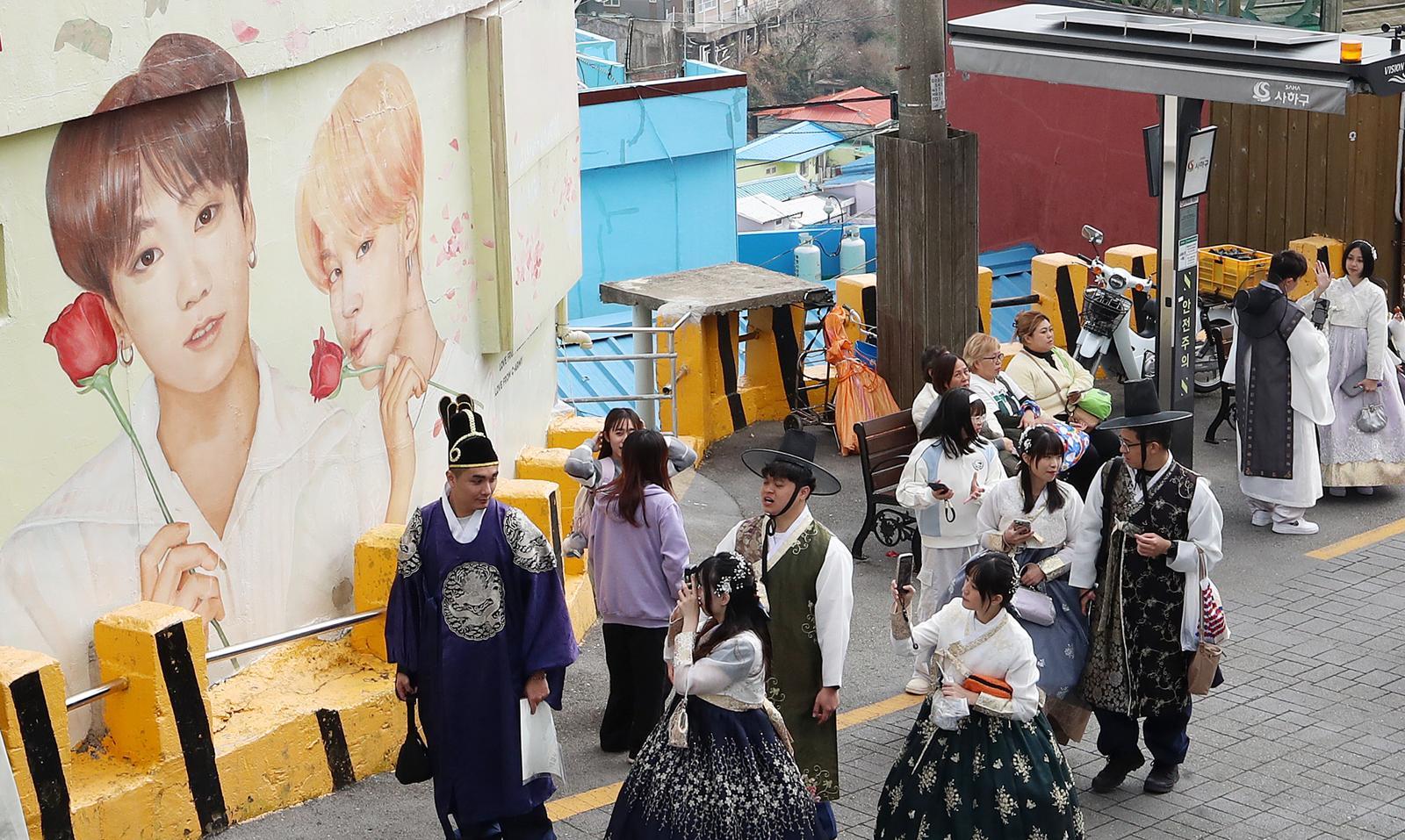 부산 서구 감천문화마을에서 외국인 관광객들이 부산이 고향인 BTS 멤버 정국·지민이 그려진 대형 벽화를 배경으로 기념촬영을 하고 있다. 2026.3.19 ⓒ 뉴스1