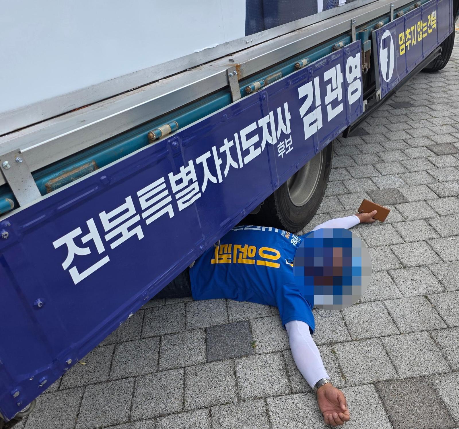 유세차 밑에 드러눕고 1일 오전 전북 전주시 효자동에서 더불어민주당 이원택 전북도지사 후보 측 선거운동원이 무소속 김관영 후보의 유세차 아래에 드러누워 있다. 선거운동원은 김 후보 측과 유세차 자리 선정 문제로 갈등을 빚다 이같이 행동한 것으로 알려졌다.  뉴스1