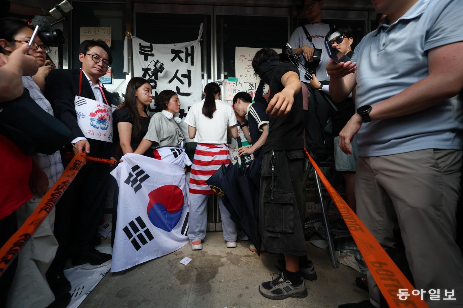 6.3지방 선거에서 투표용지가 부족한 사태에 대해 부정선거라고 주장하는 시민들이 서울 송파구 개표소인 올림픽공원 내 핸드볼경기장 출입을 봉쇄한 가운데 16일 오후 14시 50분 시민 한 명이 문을 가로 막아 체육회 인원들과 국민의힘 의원들이 건물 안으로 들어가지 못하고 있다.  변영욱 기자 cut@donga.com