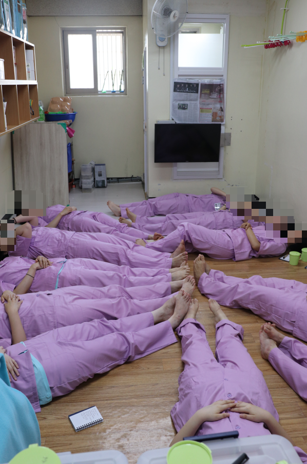 17일 수용복을 착용한 기자단이 청주여자교도소 수용자들이 생활하는 16.5㎡(약 5평) 남짓한 혼거실에 누워 ‘과밀 수용’을 경험해 보고 있다. 법무부 제공