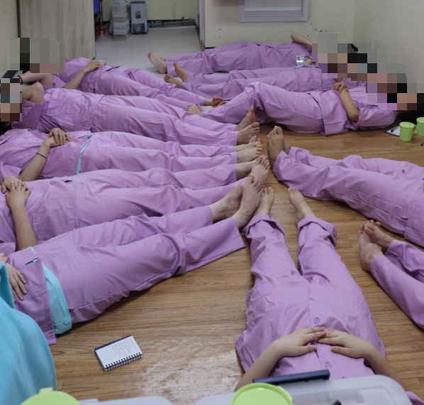 17일 수용복을 착용한 기자단이 청주여자교도소 수용자들이 생활하는 16.5㎡(약 5평) 남짓한 혼거실에 누워 ‘과밀 수용’을 경험해 보고 있다. 법무부 제공