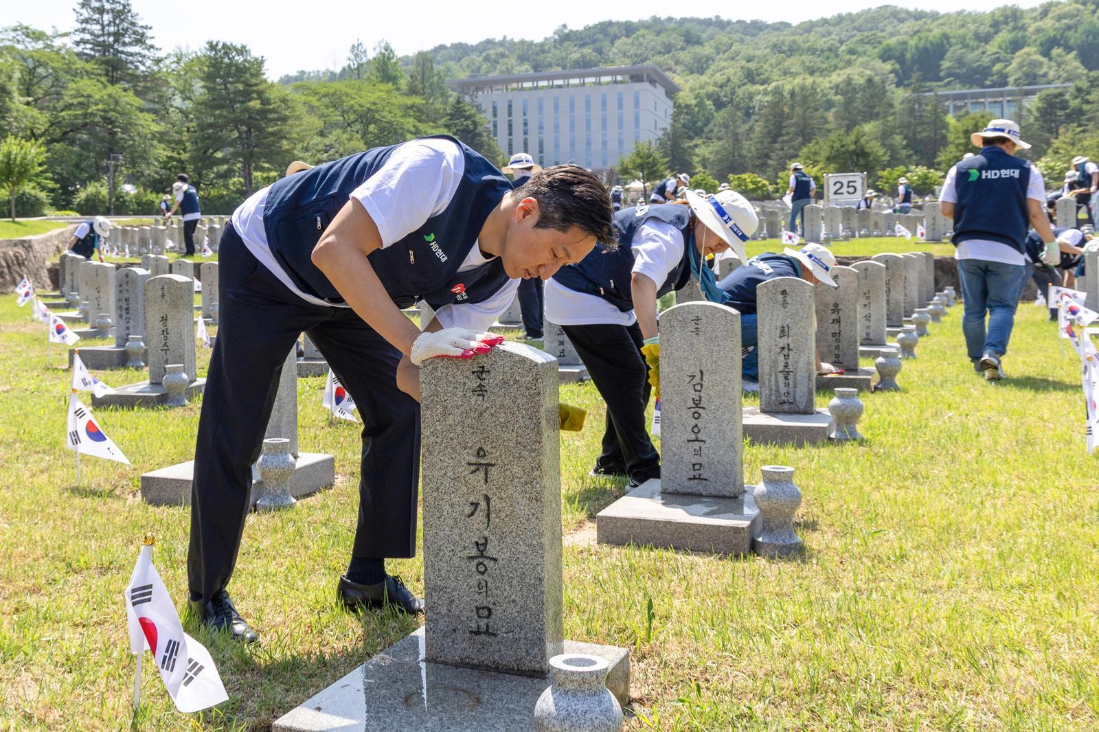 정기선 HD현대 회장이 국립서울현충원을 찾아 임직원과 함께 순직 참전 용사의 비석을 닦고 있다.