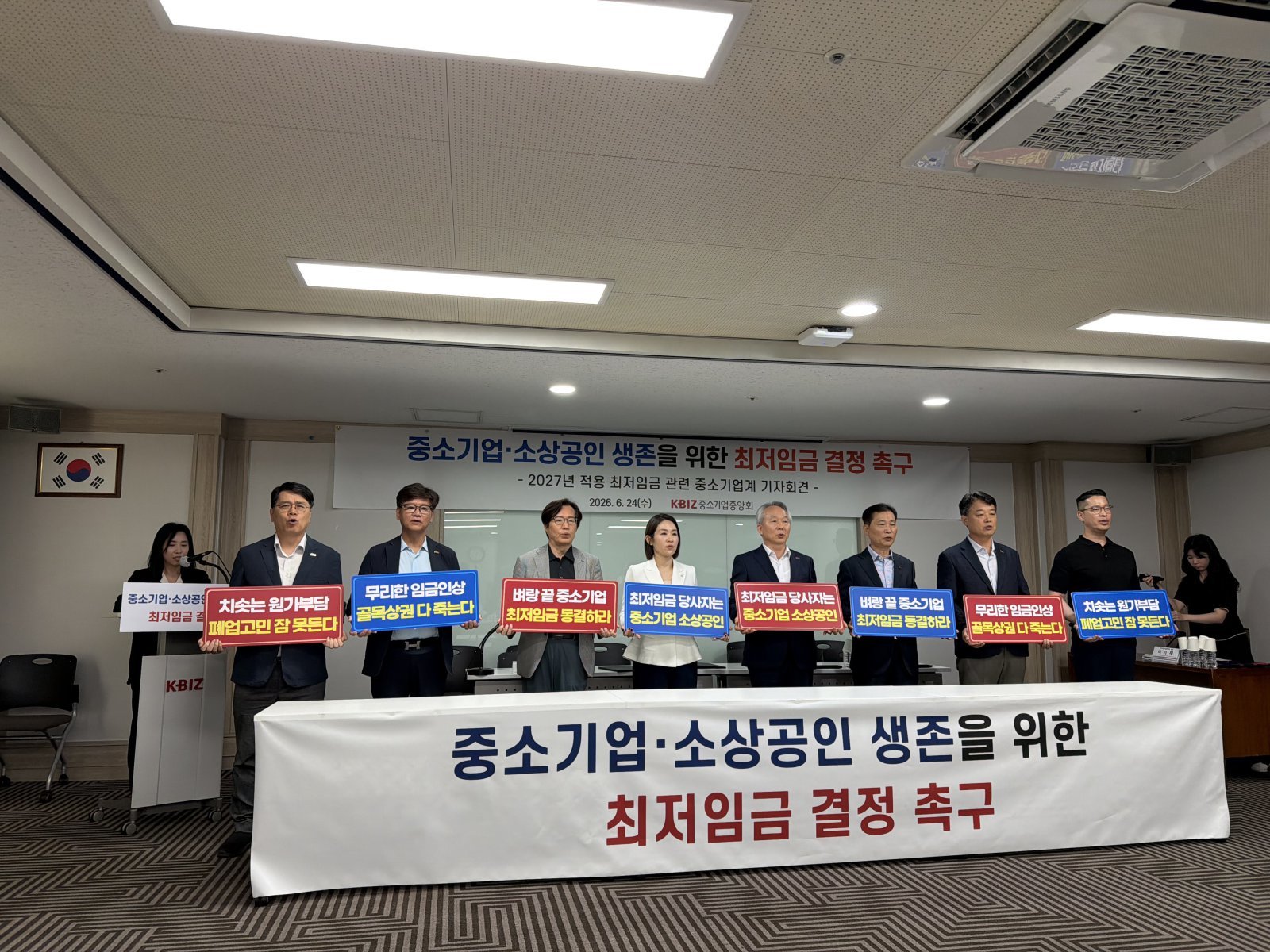 24일 서울 영등포구 중소기업중앙회에서 열린 ‘2027년 적용 최저임금 관련 중소기업계 기자회견’에서 참석자들이 피켓을 들고 최저임금 동결을 촉구하고 있다. 뉴스1