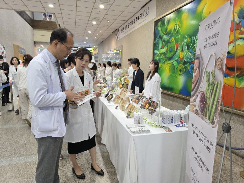 25일 경기 수원시 아주대의료원 본관에서 열린 ‘암 예방 및 치료를 위한 식단 전시회’를 찾은 방문객이 이혜경 아주대의료원 영양팀 파트장으로부터 암 예방 식단에 대한 설명을 듣고 있다. 현대그린푸드 제공