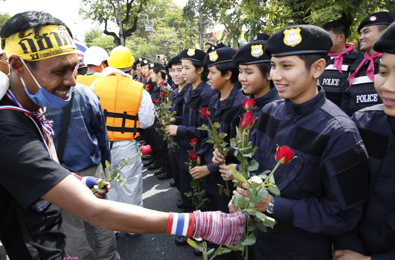 An anti-government protester gives roses to Thai policewomen outside city police headquarters in Bangkok, Thailand Tuesday, Dec. 3, 2013. — AP 뉴시스