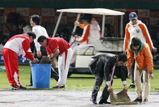 국내 야구장은 여전히 ‘천수답’이나 다름없다. 우천으로 경기가 중단된 가운데 잠시 비가 잦아들자 SK 구단 관계자들이 스펀지를 동원해 분주히 그라운드에 고인 물을 빼내고 있다. 문학 ｜ 양회성 기자 yohan@donga.com