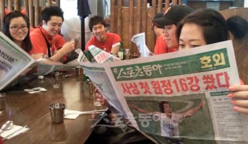 “이렇게 빠를수가” 16강 소식은 ‘스포츠동아’에서부터! 한국의 원정 첫 16강 진출이 확정된 23일 아침, 밤샘 거리 응원을 마치고 서울 광화문의 한 식당을 찾은 붉은 악마들이 때마침 배달된 스포츠동아 호외를 보며 기쁨을 만끽하고 있다.