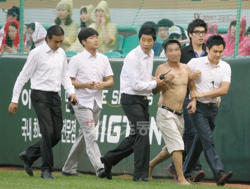 18일 인천 문학야구장에서 열린 프로야구 삼성 라이온즈와 과 SK 와이번스의 경기에서 한 팬이 그라운드에 들어와 관계자에 의해 끌려나가고 있다. 문학 | 국경원 기자 (트위터 @k1isonecut) onecut@donga.com