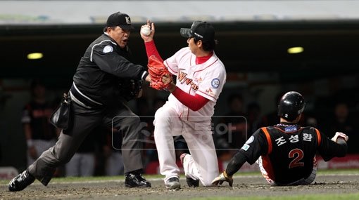 주먹을 날리듯 호쾌한 판정. 5회초 1사 2루서 롯데 김주찬의 중전안타 때 2루주자 조성환(오른쪽 끝)이 홈까지 쇄도했지만 윤희상(가운데)에게 먼저 태그되자 문승훈 주심이 힘차게 아웃을 외치고 있다. 문학 ｜ 박화용 기자 inphoto@donga.com 트위터 @seven7sola