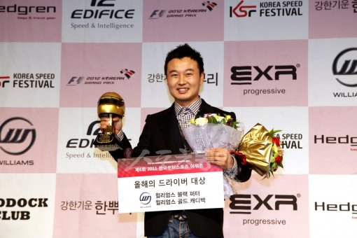 데뷔 10년 차 베테랑 드라이버 유경욱이 13일 열린 2011 한국모터스포츠 어워즈에서 ‘올해의 드라이버 대상’을 받았다. 양손에 트로피와 꽃다발을 들고 환하게 웃고 있다. 원성열 기자 sereno@donga.com 트위터 @serenowon