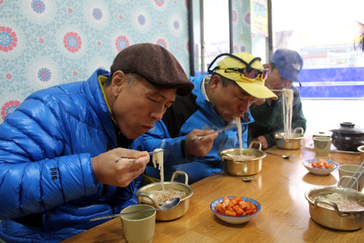 표선 해변 인근의 춘자네 멸치국수. 숙취를 말끔히 날려버리는 깨끗하고 깊은 국물맛에서 30여 년 한 자리에서 국수를 팔아 온 내공을 엿볼 수 있었다. 허영만 화백(왼쪽)과 이진원(가운데)이 국수를 맛보고 있다.