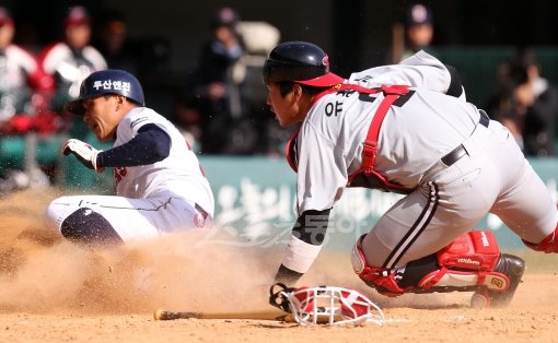 LG 김기태 감독은 시범경기에서 포수들을 골고루 기용하며 안방마님 옥석가리기를 하고 있다. 마땅한 주전 포수가 없어 꺼내든 고육지책. 21일 잠실 두산전에 교체 투입된 유강남(오른쪽)이 7회 수비 때 상대 주자 이종욱에게 홈을 내주고 있다. 잠실 ｜ 김종원 기자 won@dona.com 트위터 @beanjjun