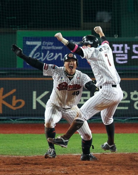 롯데 홍성흔(왼쪽)이 12일 준PO 4차전 연장 10회말 두산 포수 양의지의 실책으로 박준서(오른쪽)가 끝내기 득점을 올리자 함께 양팔을 들어 기쁨의 환성을 지르고 있다. 사진제공|스포츠코리아