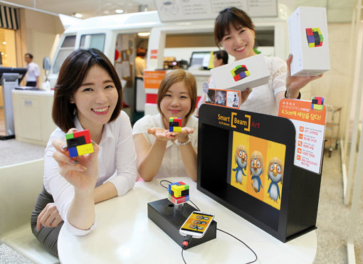 SK텔레콤의 스마트폰 빔 프로젝터 ‘스마트빔 아트’. 스마트폰과 연결하면 영화, DMB 등의 콘텐츠를 별도의 프로그램 설치없이 케이블 연결만으로 볼 수 있다. 3미터 거리에서 100인치의 대화면 감상도 가능하다. 사진제공｜SK텔레콤