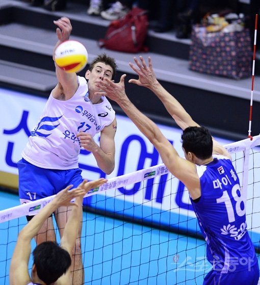 우리카드 루니(왼쪽)가 V리그 남자부 경기에서 대한항공 마이클의 블로킹을 피해 스파이크하고 있다. 루니는 26득점으로 강만수 감독에게 30주년 결혼기념일 선물을 안겼다. 아산|김종원 기자 won@donga.com 트위터 @beanjjun