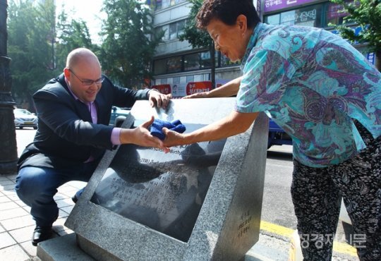 미국 인기 만화작가 온리 콤판이 8일 서울 중구 이순신 장군 생가터를 방문해 30년간 매일 이순신 장군 표석을 닦아온 \'이순신 할머니\' 이종임씨와 함께 표석을 닦고 있다. 사진= 여성경제신문 제공