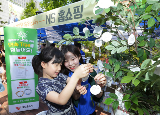 NS홈쇼핑 ‘2017 환경의 날 생태 환경 축제, 손바닥농장 팜팜’ 참가 어린이가 ‘환경보호 실천을 위한 약속 나무’에 다짐카드를 걸고 있다. 사진제공 l NS홈쇼핑