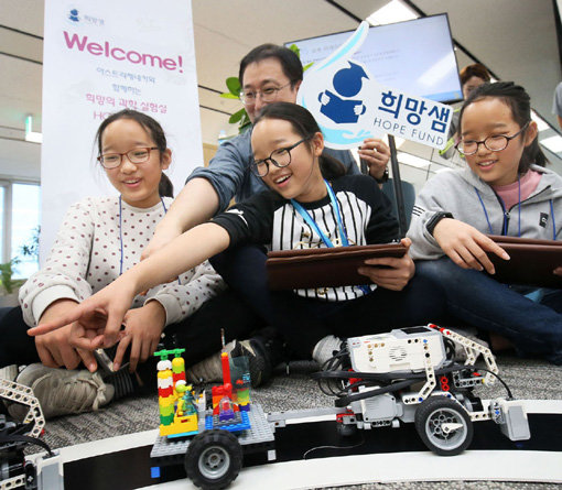 한국아스트라제네카의 ‘희망의 과학 실험실’ 행사에서 희망샘 장학생들이 코딩 작업을 통해 동선을 설계한 열차가 레일 위를 달리고 있는 모습을 보며 기뻐하고 있다.