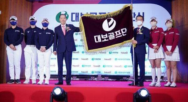 대보그룹 최등규 회장(왼쪽에서 4번째)이 18일 서원밸리컨트리클럽에서 열린 대보골프단 창단식에서 이석호 단장에게 단기를 전달한 뒤 기념 포즈를 취하고 있다. 사진 왼쪽부터 오승현, 고군택, 최민철, 최 회장, 이 단장, 김지현, 김윤교. 사진제공 | 대보그룹