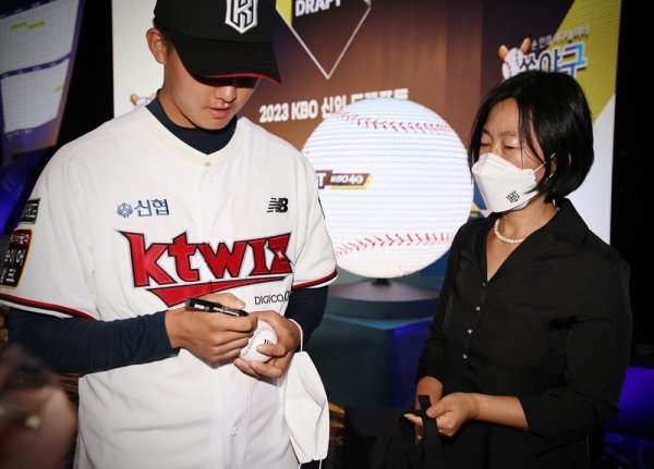 어머니 이현희 씨에게 건넬 공에 사인하고 있는 성남고 김건웅. 사진제공 | KT 위즈