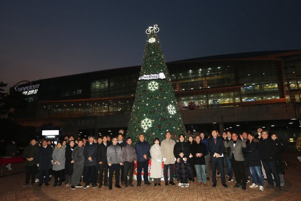 크리스마스트리 점등식에 참가한 지역주민, 고객, 선수 등이 모여 기념사진을 촬영하고 있다.