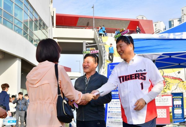 김한종 장성군수(사진 우측)가 지난 10일 광주 기아 챔피언스필드 경기장 입구에 마련된 부스에서 군 공직자들과 홍보 리플릿을 나눠주며 꽃길축제를 홍보하고 있는 모습. 사진제공ㅣ장성군