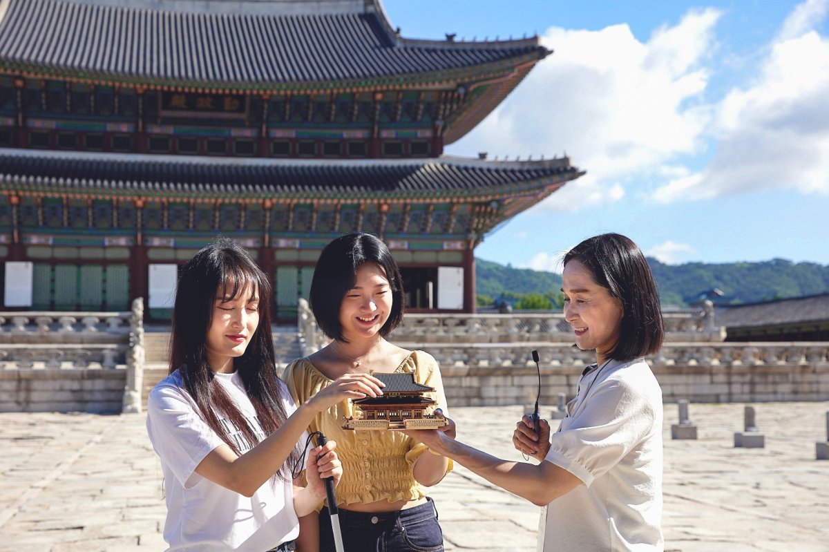 서울 현장영상해설 투어 참가자가 경복궁 근정전 모형을 만지며 건축 특징에 대한 해설을 듣고 있다. 사진제공 | 서울관광재단