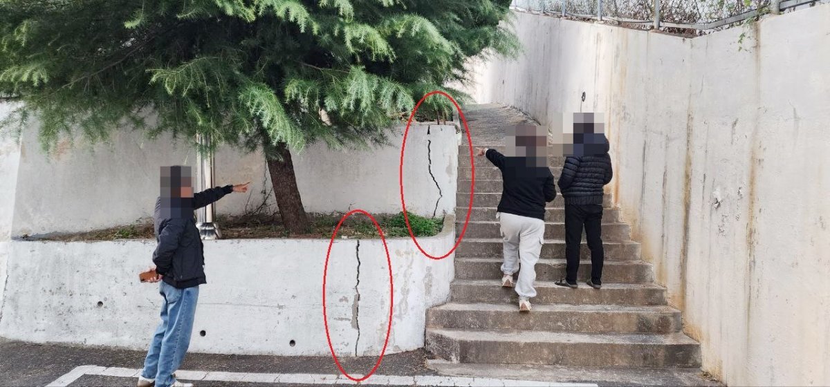 주민들이 최근에 금이 간 담벼락을 가리키고 있다.