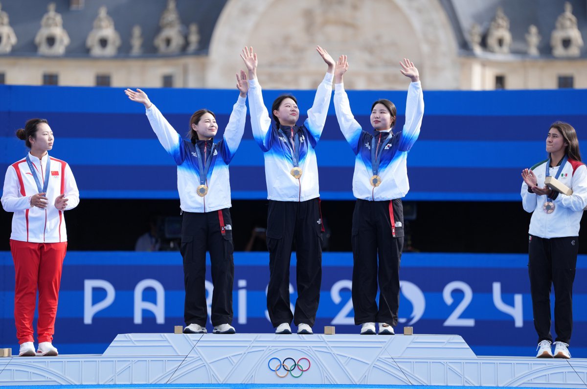 전훈영, 임시현, 남수현(왼쪽 2번째부터 4번째까지)이 29일(한국시간) 레쟁발리드양궁장에서 열린 중국과 2024파리올림픽 양궁 여자단체전 결승에서 승리한 뒤 시상대에 올라 환호에 답하고 있다. 파리｜신화뉴시스