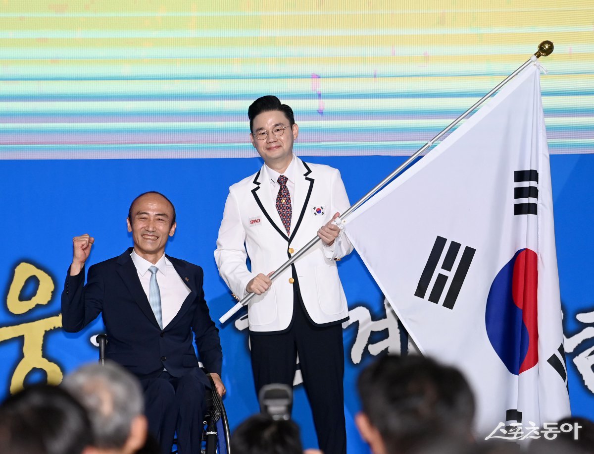 12일 서울 송파구 올림픽파크텔에서 열린 ‘2024 파리 패럴림픽 대한민국 선수단 결단식’에서 정진완 대한장애인체육회장이 배동현 선수단장에게 단기를 전달하고 있다.  김종원 기자 won@donga.com