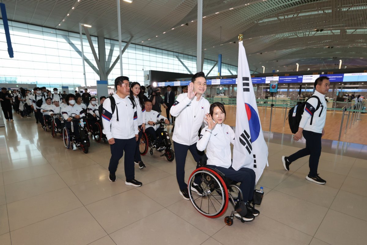 2024파리패럴림픽에 참가하는 한국 선수단 본진이 21일 인천국제공항에서 출영식을 마치고 출국장으로 향하고 있다. 태극기를 든 휠체어펜싱대표팀 조은혜와 배동현 선수단장이 환송객을 향해 손을 흔들고 있다. 사진 제공｜대한장애인체육회