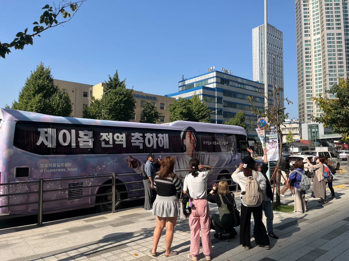 서울 용산구 하이브 사옥 앞에서 제이홉을 기다리고 있는 팬들과 그의 전역을 축하하는 메시지가 래핑된 대형 버스. 사진제공|빅히트 뮤직