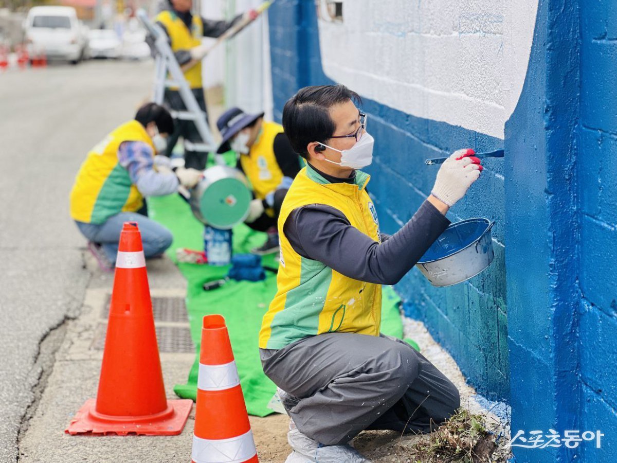 신천지자원봉사단 마산지부 봉사자들이 푸른색 페인트로 벽화를 그리고 있다. (사진제공=신천지자원봉사단 마산지부)