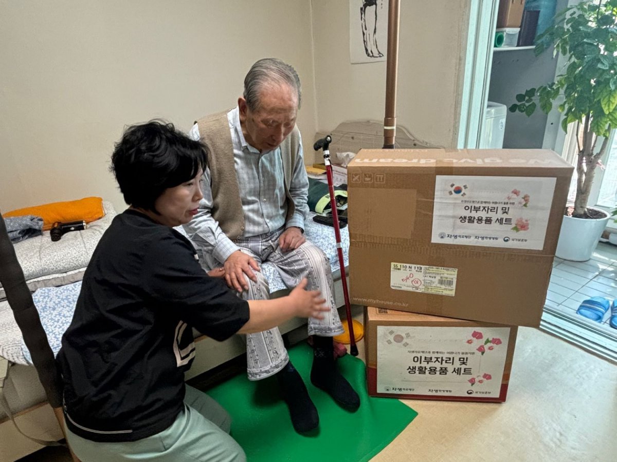 자생의료재단 관계자가 독립유공자 어르신 가정을 방문해 여름 침구류 세트와 생필품을 전달하고 있다 사진제공|자생의료재단