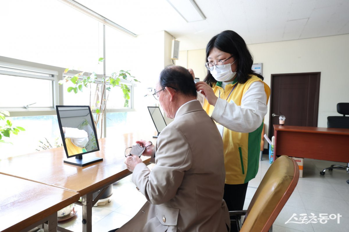 신천지자원봉사단 부산서부지부가 ‘영원히 빛날 평화의 영웅’ 활동을 진행한 가운데 한 봉사자가 어르신의 머리를 정리하고 있다. (사진제공=신천지자원봉사단 부산서부지부)
