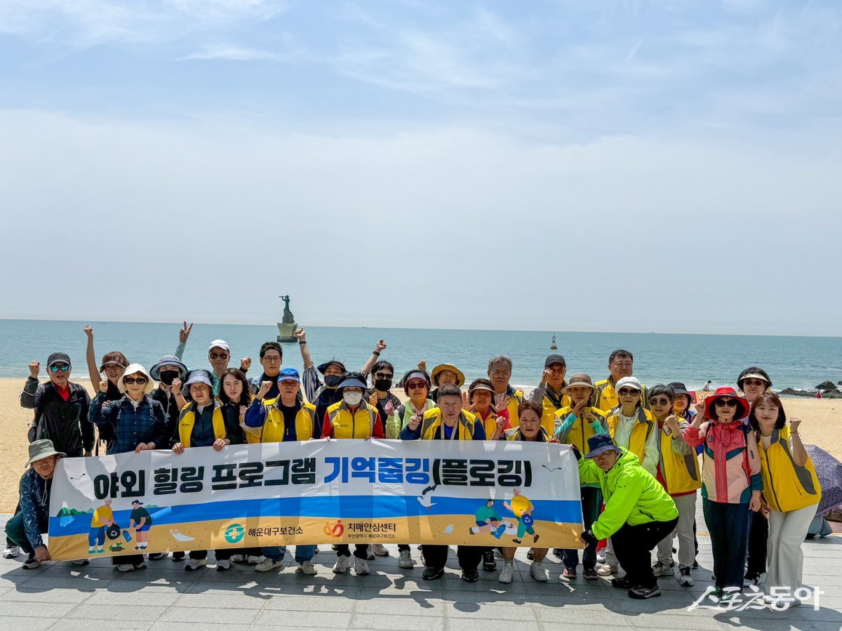 부산 해운대구 치매안심센터가 26일 해운대해수욕장에서 치매 환자와 가족이 참여하는 ‘야외 힐링 프로그램 기억줍깅(플로깅)’를 개최한 가운데 관계자들이 기념촬영을 히고 있다. (사진제공=해운대구청)
