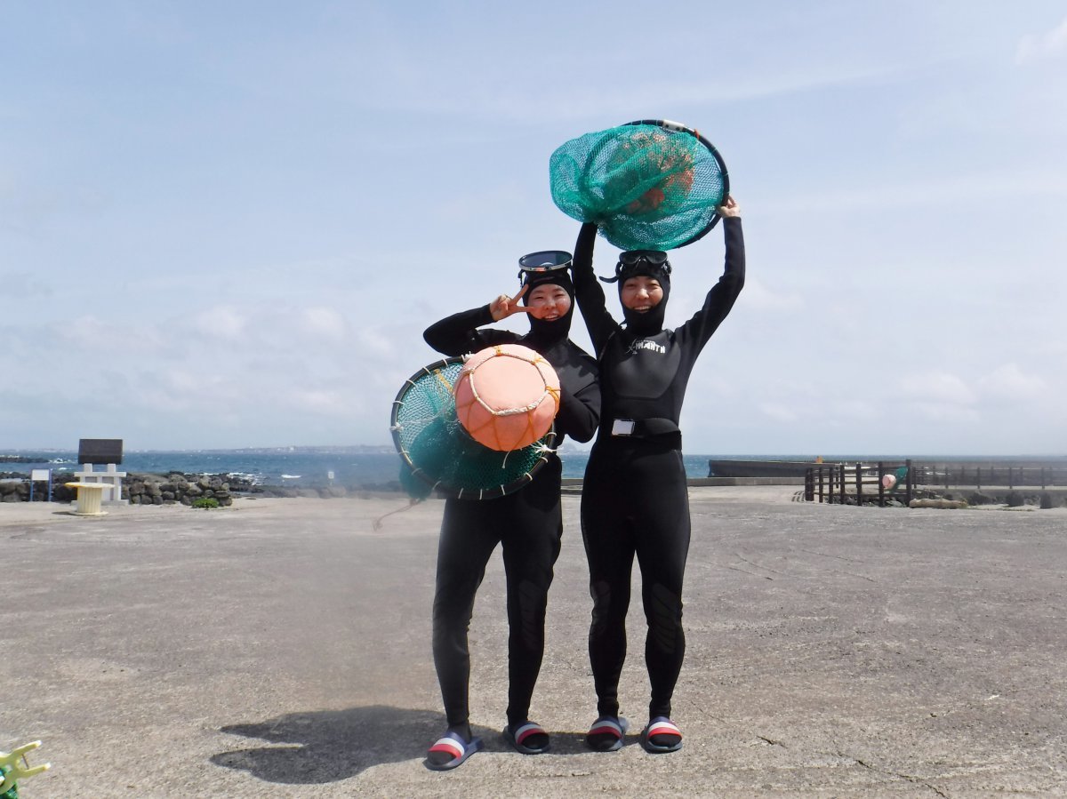 제주 하도어촌체험마을의 해녀물질체험에 참가한 관광객이 태왁과 망사리를 들고 기념사진을 찍고 있다    사진제공｜한국관광공사