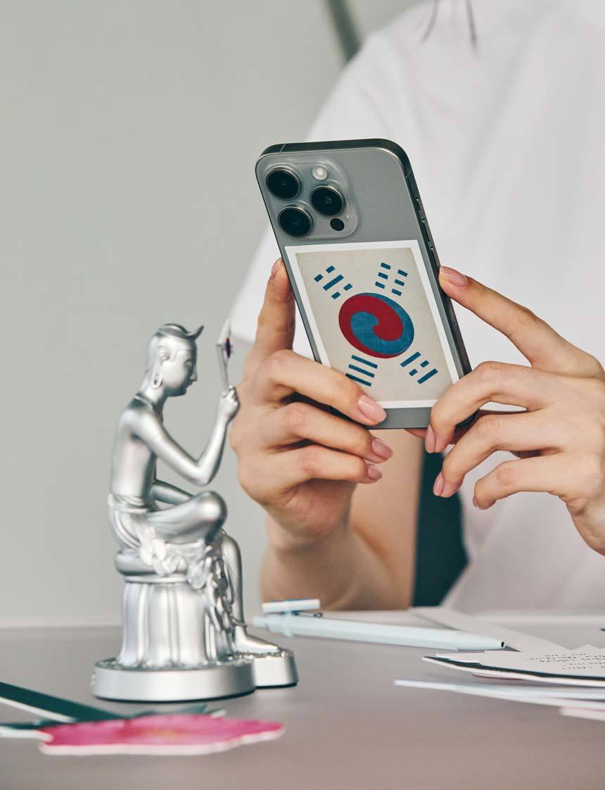 광복 80주년 기념 ‘데니 태극기 스티커’가 붙은 휴대전화와 ‘반가사유상 미니어처: 광복에디션’. 사진제공ㅣ국립박물관문화재단