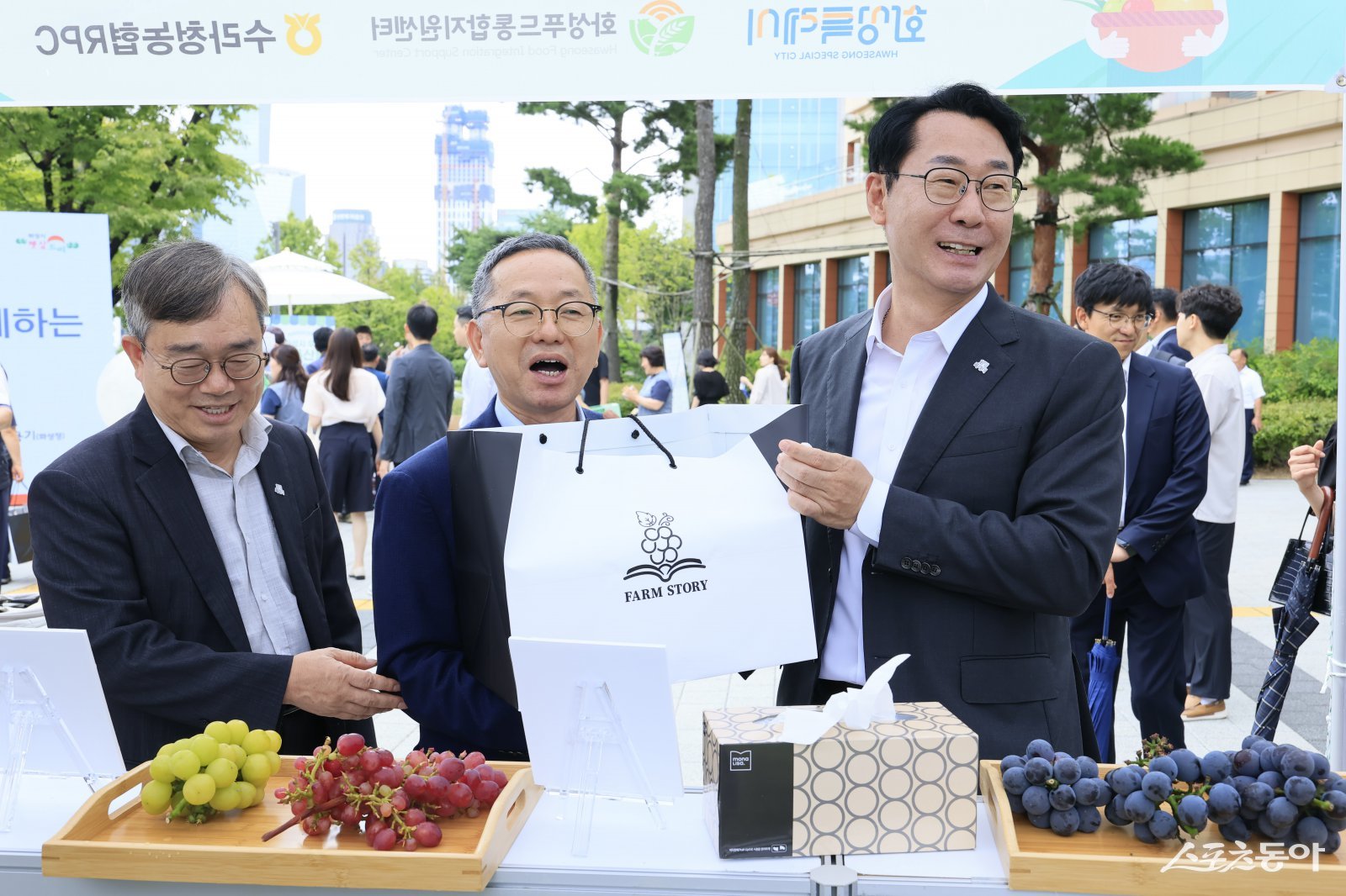 정명근 화성특례시장(사진 오른쪽 첫번째)이 지난 4일 국회 로컬푸드 직거래 장터에서 송산포도를 살펴보며 농업 관계자들과 환담을 나누고 있다. 사진제공｜화성시