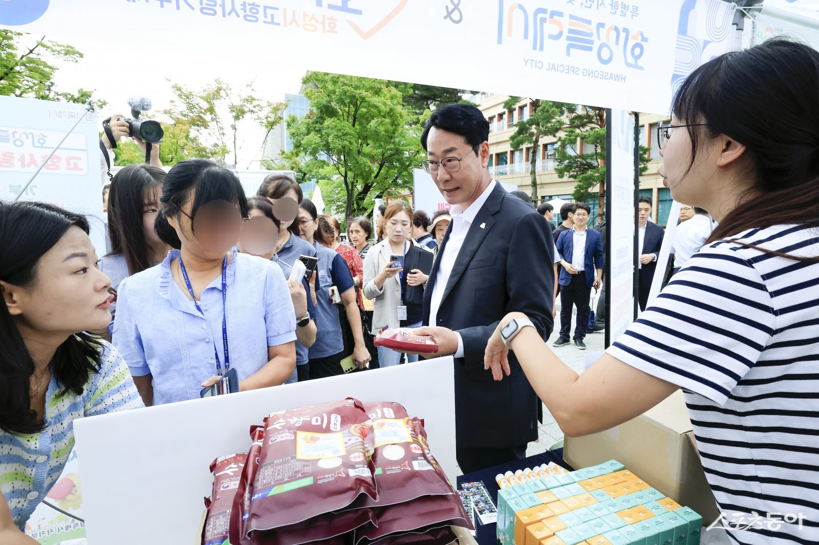 정명근 화성특례시장(사진 오른쪽 두번째)이 지난 4일 직거래 장터를 찾은 시민에게 화성특례시 대표 농산물인 수향미를 홍보하고 있다. 사진제공｜화성시